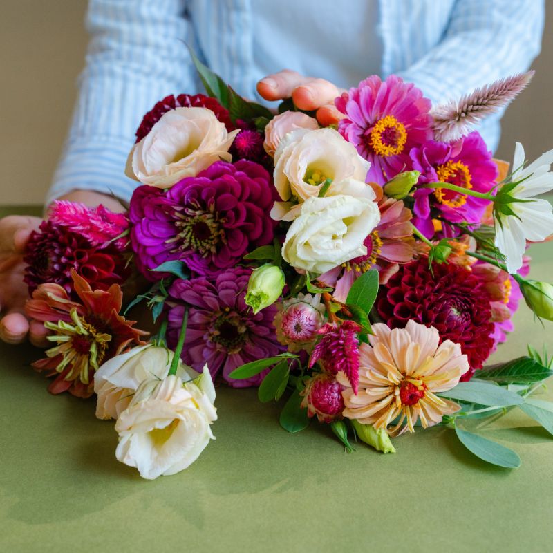 Close-up of a floral subscription bouquet of zinnia and lisianthus in red and pink